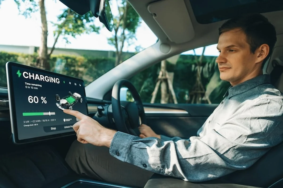 Kierowca sprawdza stan ładowania samochodu elektrycznego na ekranie aplikacji. Urządzenie pokazuje dane o ładowaniu