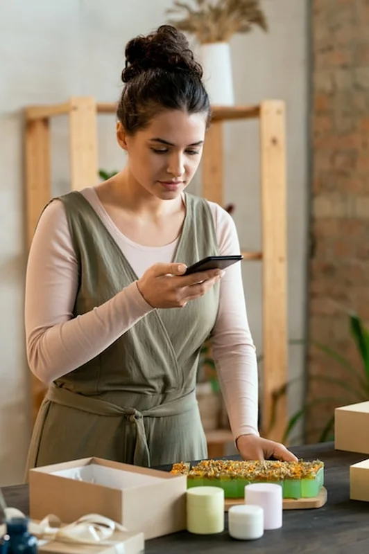 Młoda kobieta kręci wideo przy stole ze świecami i mydłem przed zapakowaniem