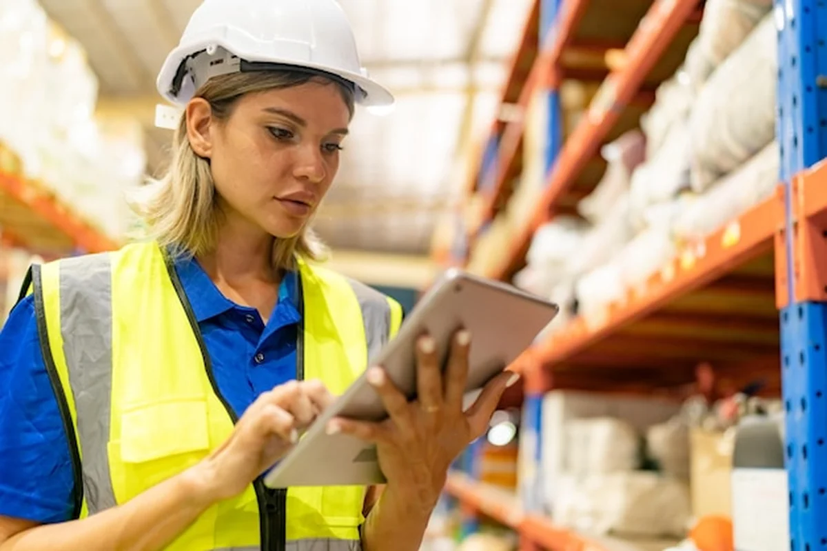 Pracownik w magazynie z listą kontrolną, sprawdzający materiał na palecie gotowy do wysyłki